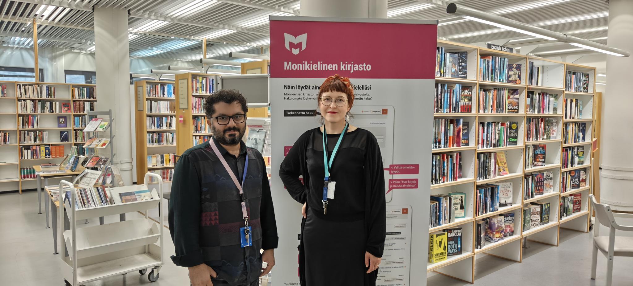 Monikielisen kirjaston kirjahyllyjen edessä kaksi henkilöä: Aram Jalal ja Minna Mohr