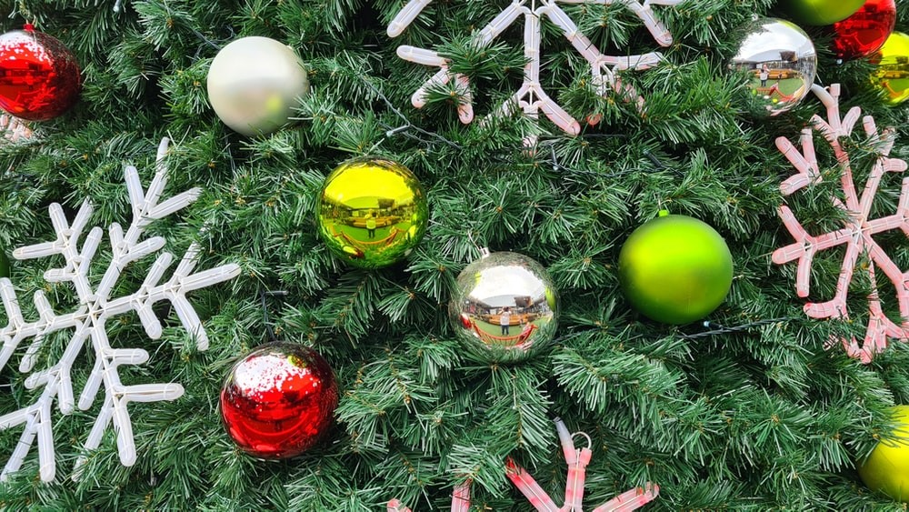 Lähikuva joulukuusen oksista, joissa värikkäitä joulupalloja. Kuva: Unsplash.